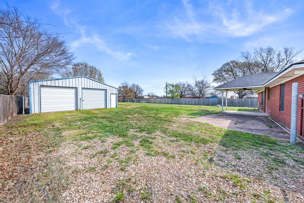 903 Amy Way Bonham, TX 75418 - Photo 4 of 27 Fenced backyard with a patio area, an outdoor structure, and a detached garage