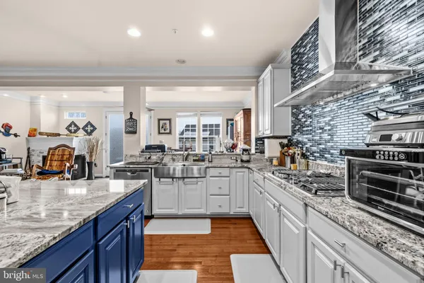 a large kitchen with stainless steel appliances granite countertop a lot of counter space and wooden floor