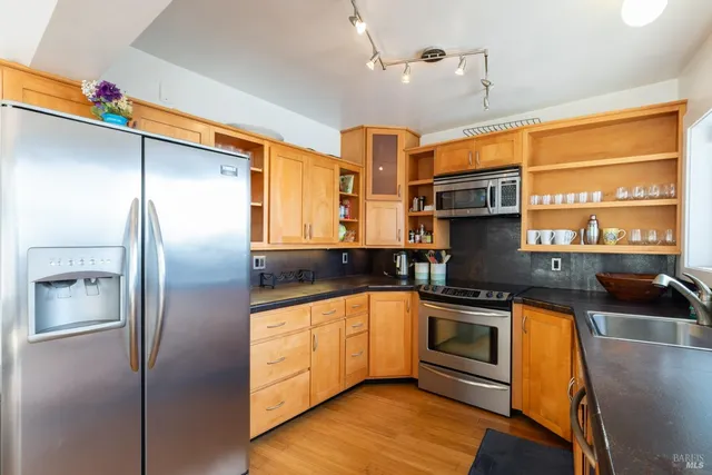a kitchen with stainless steel appliances granite countertop a sink a stove and a refrigerator