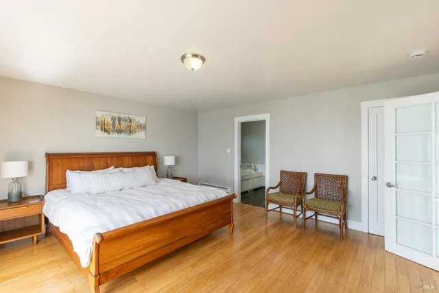 a bedroom with a bed a chair and a potted plant on dresser