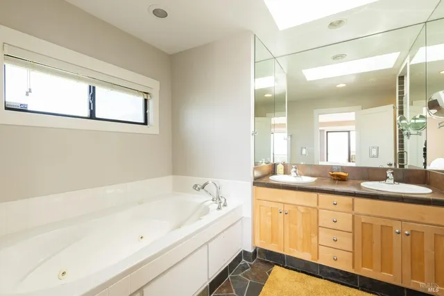 a bathroom with a granite countertop tub sink and mirror