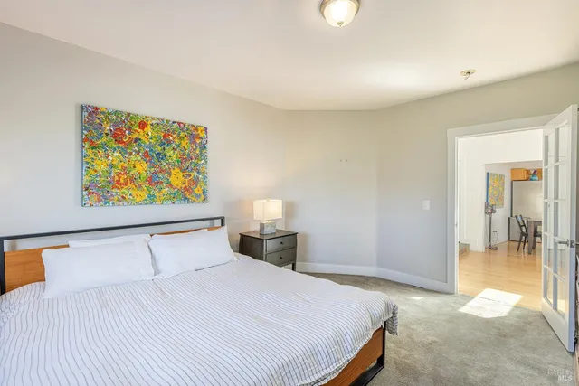 a bedroom with a bed and painting on the wall