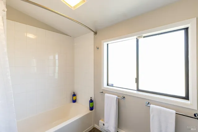 a bathroom with a bathtub a shower and a window