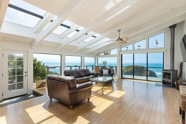 a living room with furniture floor to ceiling window and wooden floor