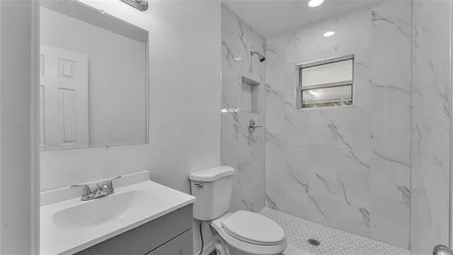 a bathroom with a toilet sink vanity and shower