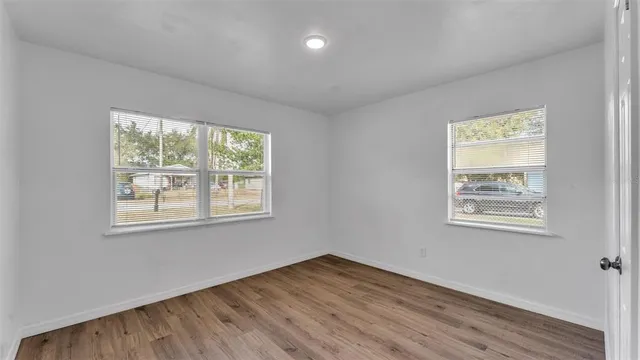 a view of an empty room with wooden floor and a window