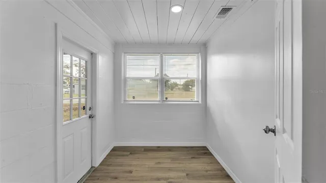 a view of an empty room with wooden floor and a window