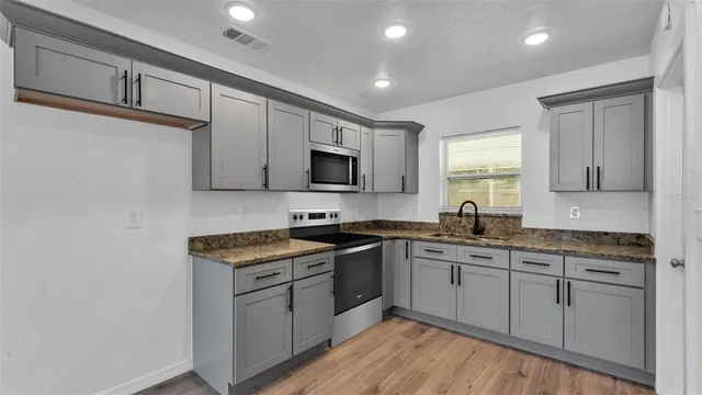 a kitchen with stainless steel appliances granite countertop a sink stove cabinets and refrigerator