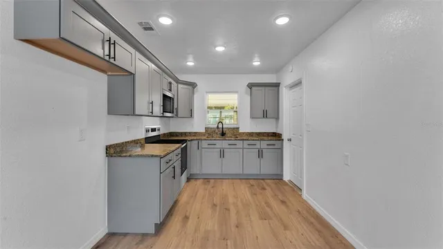 a kitchen with granite countertop a sink cabinets stainless steel appliances and a counter top space