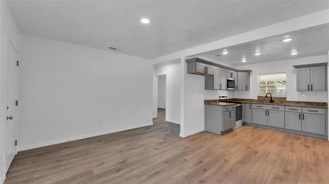 a large kitchen with a wooden floor and stainless steel appliances