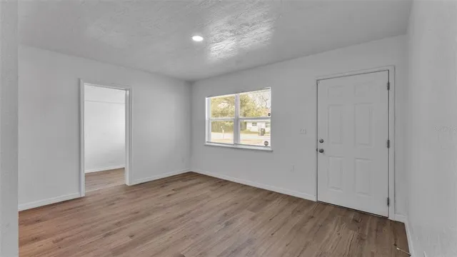 an empty room with wooden floor and windows