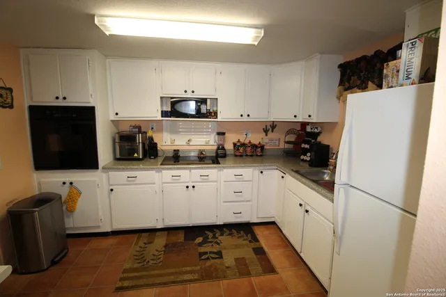 a kitchen with stainless steel appliances a refrigerator sink stove and white cabinets