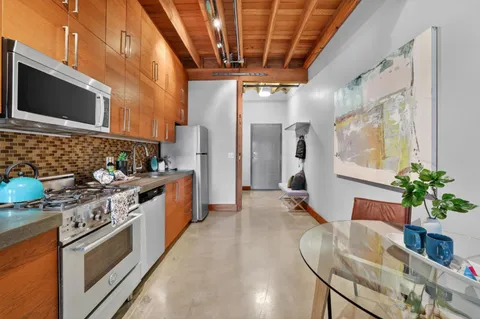 a kitchen with stainless steel appliances granite countertop a stove a sink dishwasher and a flat screen tv