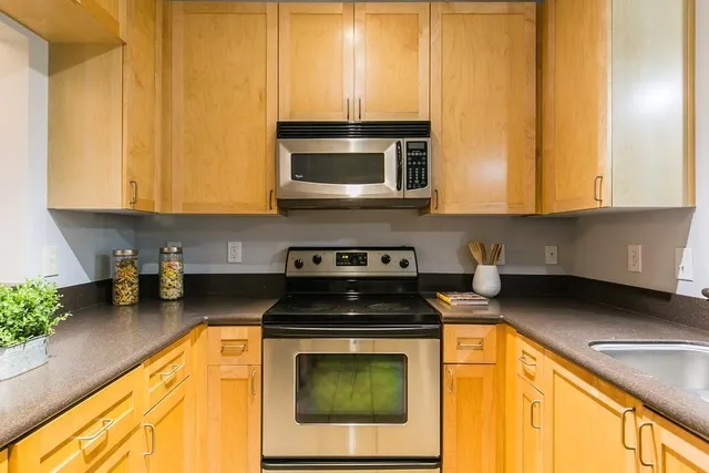 a kitchen with stainless steel appliances granite countertop a stove a sink and a microwave