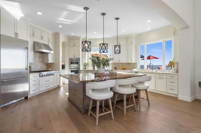 a kitchen with stainless steel appliances kitchen island granite countertop a dining table chairs and sink