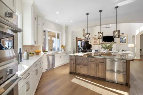 a kitchen with stainless steel appliances granite countertop a sink a stove and a wooden floor