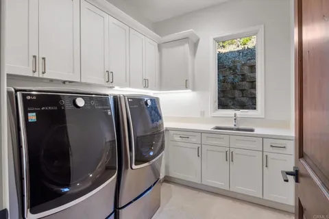 a utility room with stainless steel appliances granite countertop a sink and washer