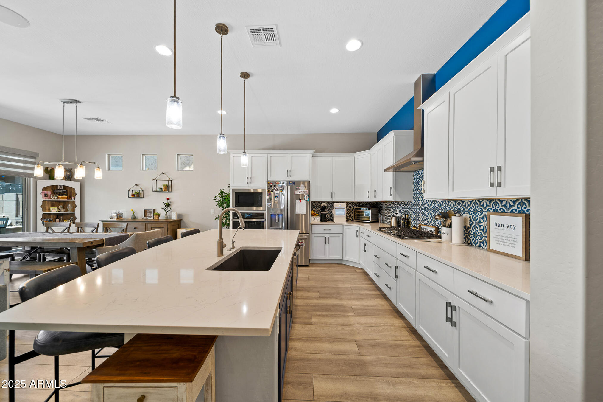 4155 East Jesse Street Gilbert, AZ 85295 - Photo 19 of 71 a large kitchen with kitchen island a stove a sink a refrigerator and white cabinets with wooden floor