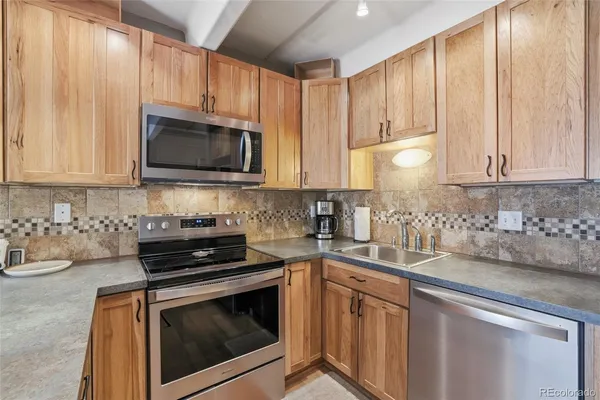 a kitchen with granite countertop white cabinets sink and stainless steel appliances