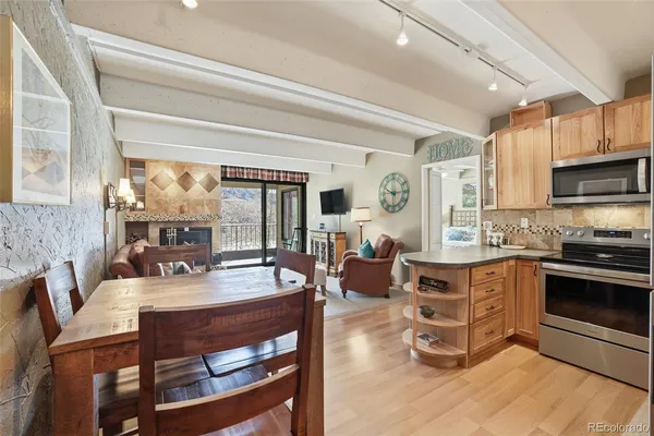 a dining hall with stainless steel appliances granite countertop a dining table and chairs with wooden floor