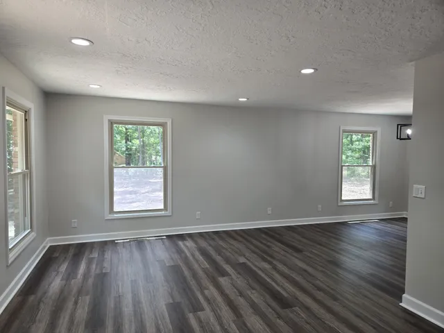 a view of a livingroom with a fireplace a chandelier fan and wooden floor