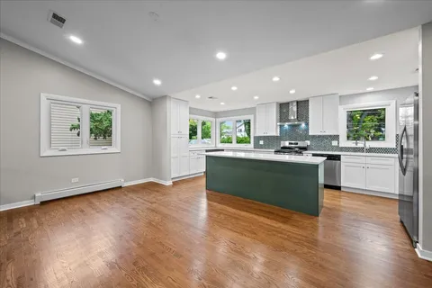 a kitchen with stainless steel appliances granite countertop a stove top oven a sink dishwasher and a refrigerator with wooden floor