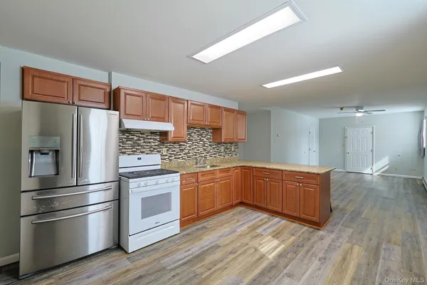 a kitchen with stainless steel appliances kitchen island granite countertop a refrigerator and a stove top oven
