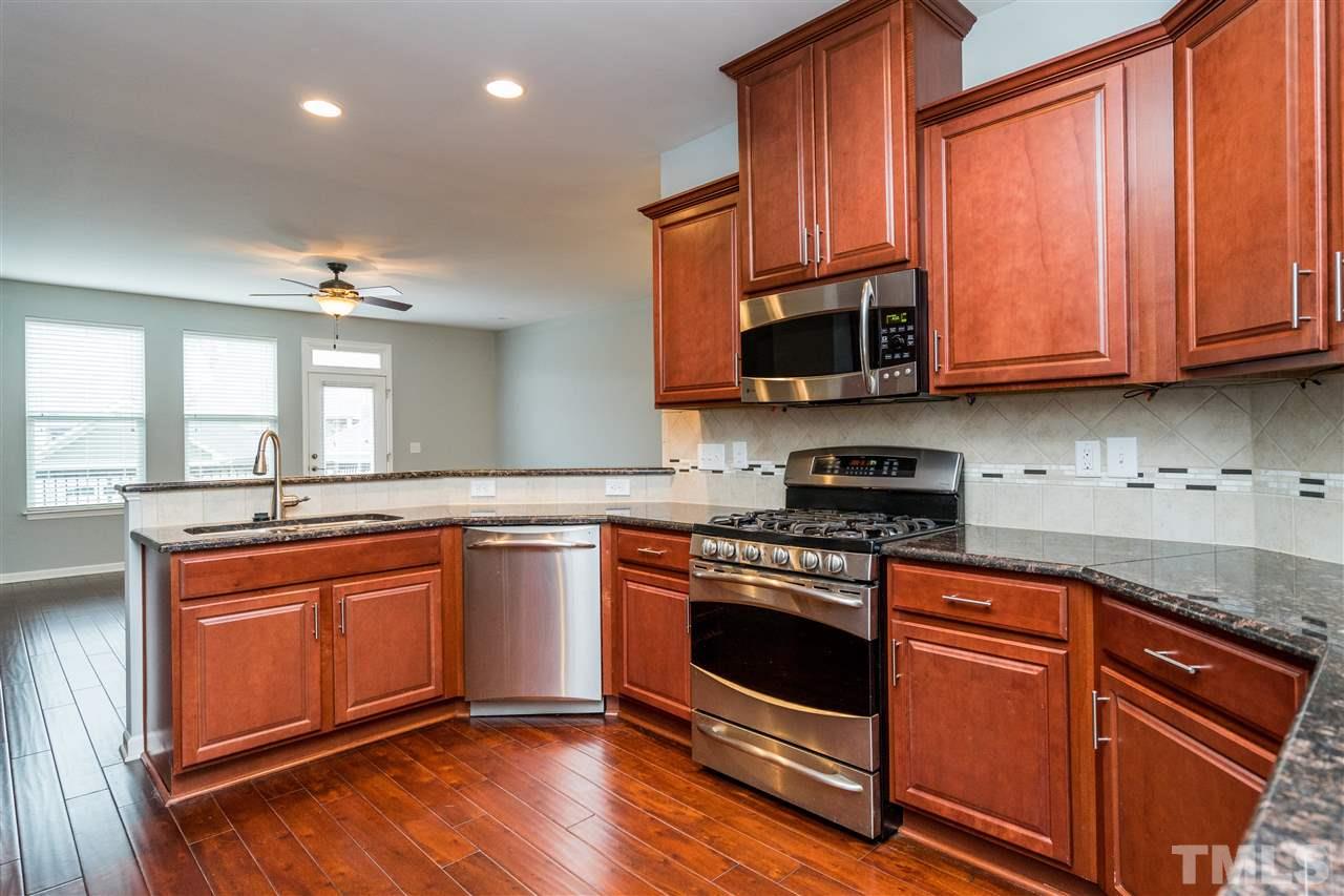 1539 Rodessa Run Raleigh, NC 27607 - Photo 12 of 25 a kitchen with stainless steel appliances granite countertop wooden cabinets a stove a sink and dishwasher with wooden floor
