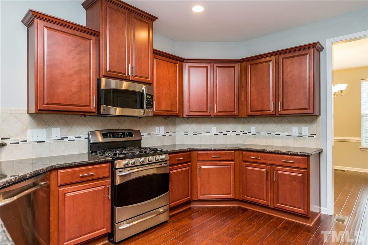 1539 Rodessa Run Raleigh, NC 27607 - Photo 13 of 25 a kitchen with stainless steel appliances granite countertop wooden cabinets a stove a sink and dishwasher with wooden floor