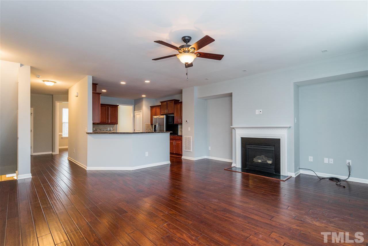 1539 Rodessa Run Raleigh, NC 27607 - Photo 8 of 25 a view of a livingroom with a fireplace a ceiling fan and a kitchen view
