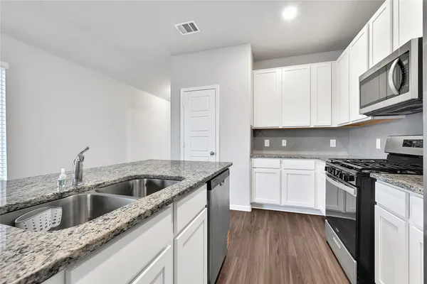 a kitchen with stainless steel appliances granite countertop a sink a stove and cabinets