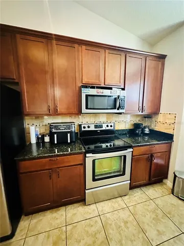 a kitchen with granite countertop a stove top oven microwave and cabinets