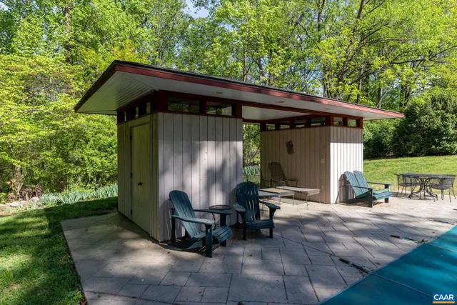a backyard of a house with table and chairs with plants and wooden fence