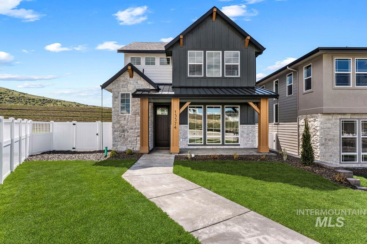 View of front of property with a standing seam roof, stone siding, a gate, and board and batten siding