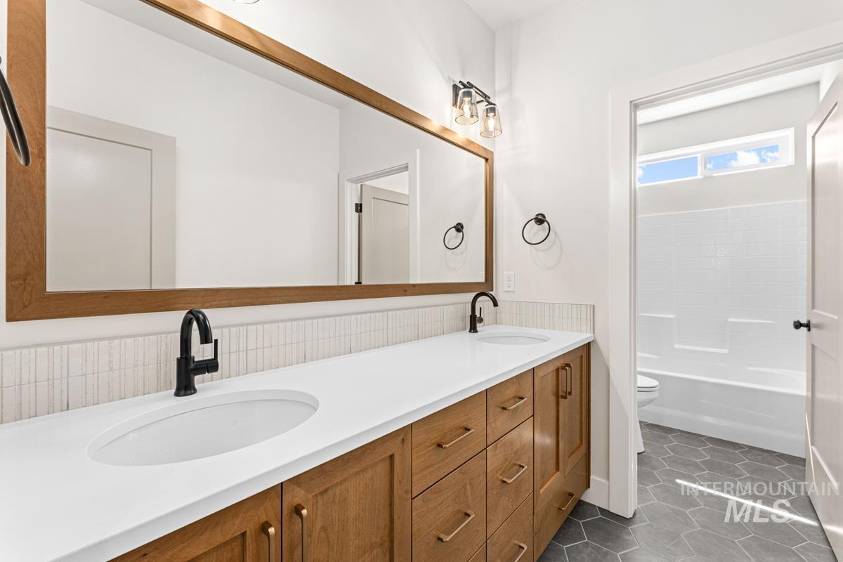 13374 North Spring Creek Way Boise, ID 83714 - Photo 27 of 49 Full bathroom with double vanity, dark tile patterned flooring, and shower / washtub combination