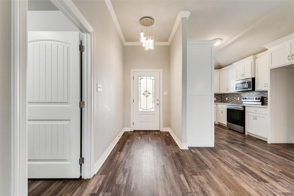 625 Copenhavr Street Pilot Point, TX 76258 - Photo 5 of 20 Foyer entrance with dark wood-style floors, crown molding, and a chandelier