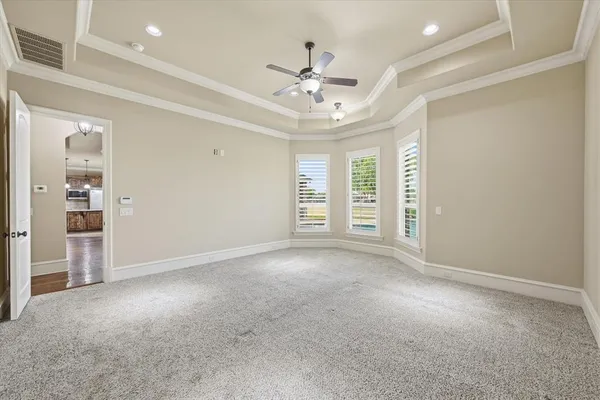 an empty room with windows and ceiling fan