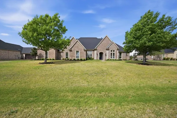 a front view of a house with a garden and tree