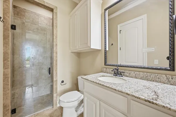 a bathroom with a granite countertop sink a toilet and shower