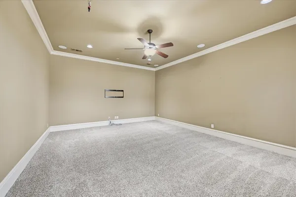 an empty room with chandelier fan and windows