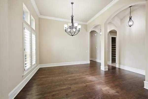 a view of a room with wooden floor chandelier and windows