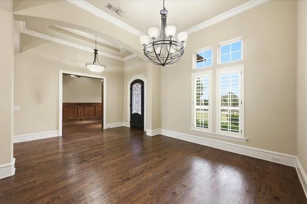 a view of an empty room with wooden floor fan and a window