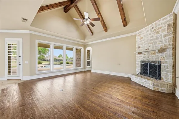 an empty room with wooden floor fireplace and windows