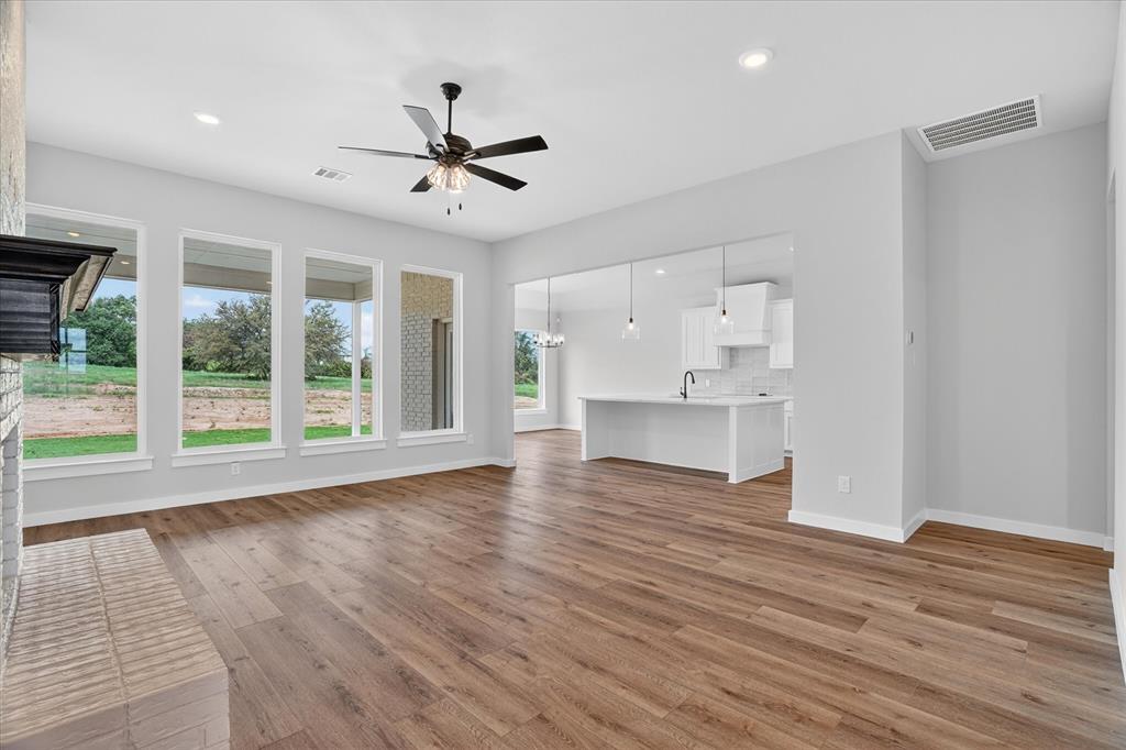 317 Skeen Peak Springtown, TX 76082 - Photo 5 of 31 Spacious living area featuring wood-finish flooring, a white brick fireplace with a dark mantel, and a multi-pane window array