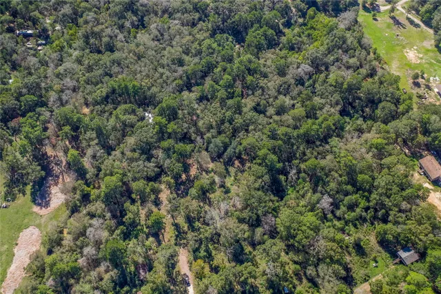 an aerial view of residential house with outdoor space and trees all around