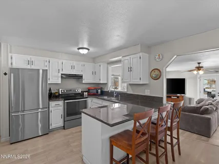 a kitchen with stainless steel appliances granite countertop a sink a stove a refrigerator cabinets and chairs