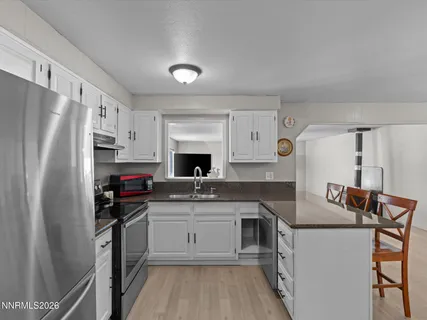 a kitchen with stainless steel appliances granite countertop a sink stove refrigerator and cabinets