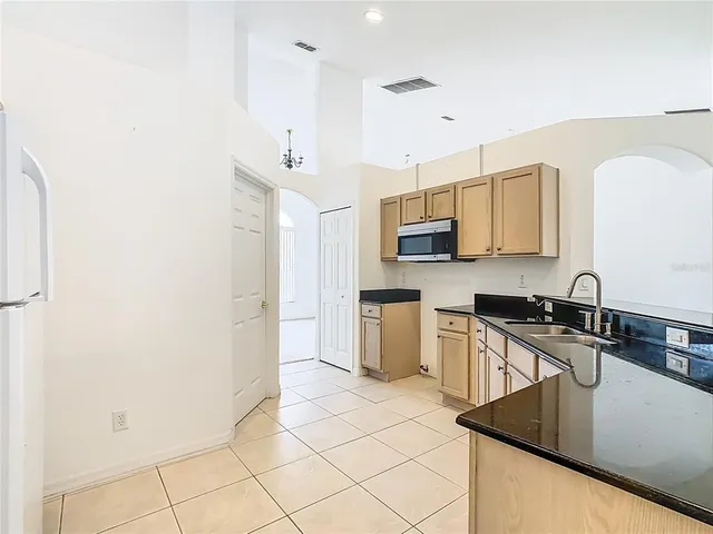 an empty room with chandelier fan and windows
