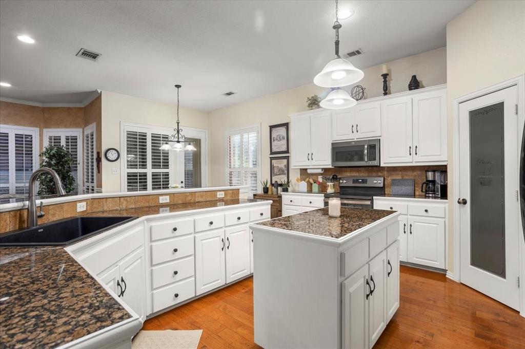 8312 Teja Trail Benbrook, TX 76126 - Photo 6 of 23 a large kitchen with stainless steel appliances kitchen island granite countertop a sink dishwasher a stove and a refrigerator with wooden floor