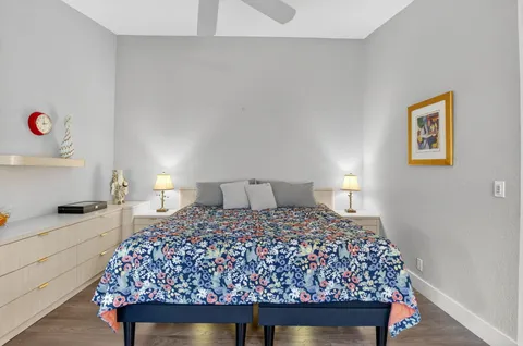 a bedroom with two bed and a painting on the wall